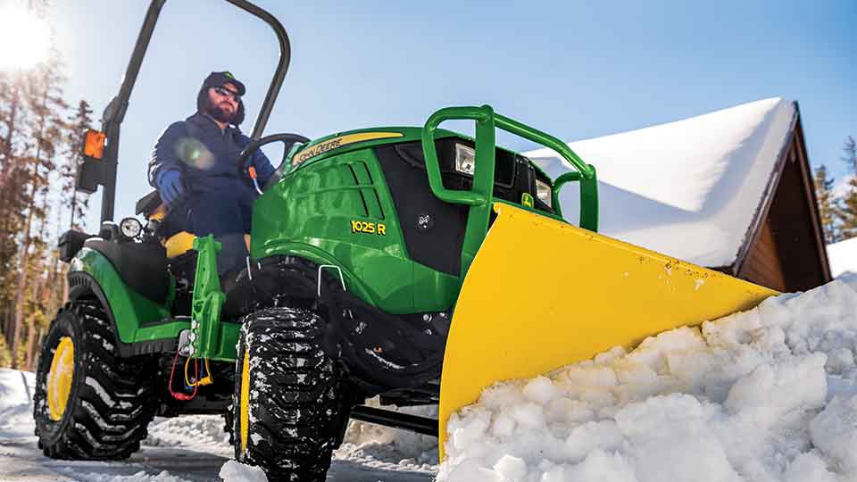 man using 1025R for pushing snow with plow