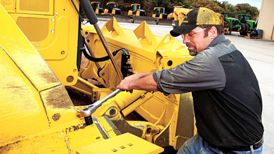 service technician working on piece of heavy machinery