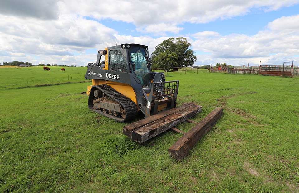 John Deere Compact Track Loader loading railroad ties used for cattle fencing.