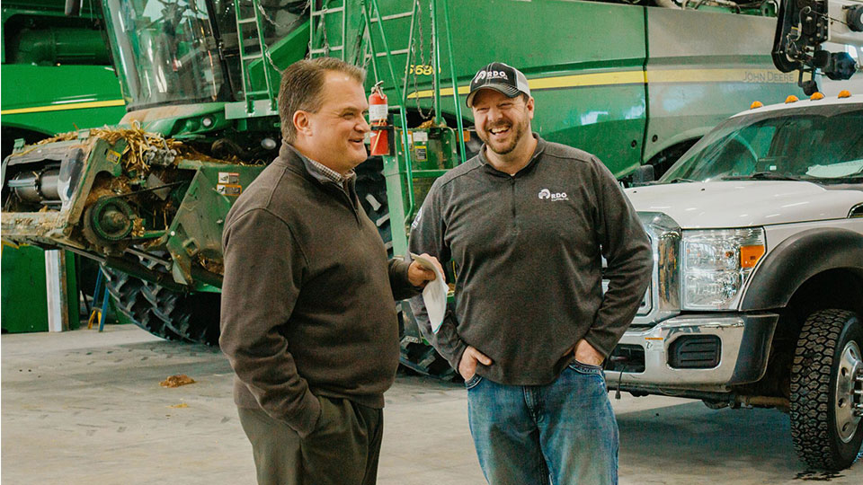 salespeople talking in service shop combine behind them