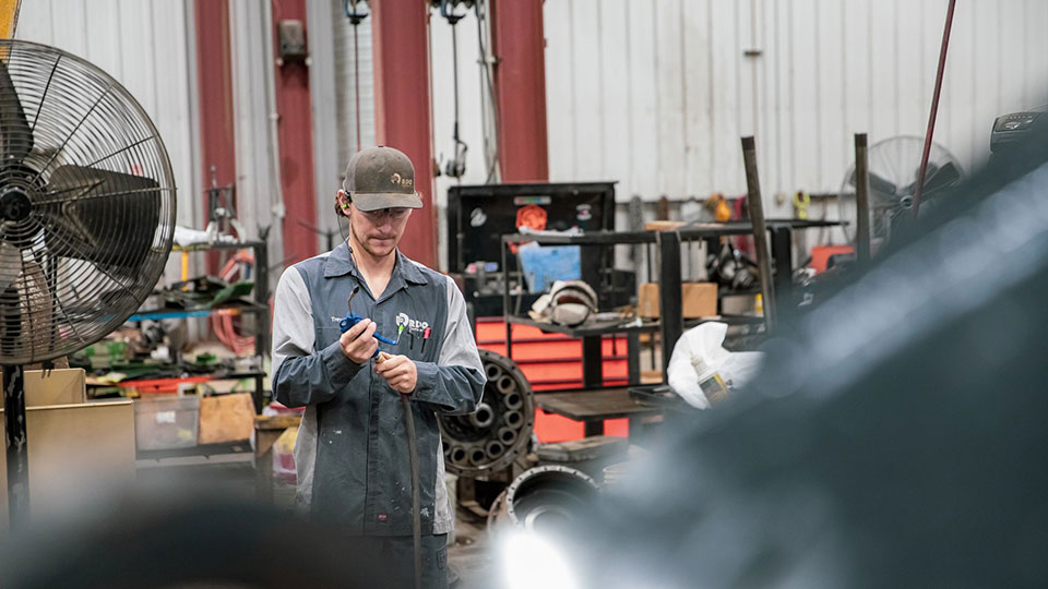 service technician holding welding gun in shop