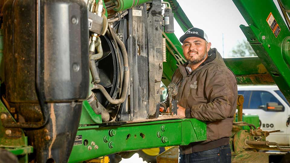 mechanic smiling while working on green equipment