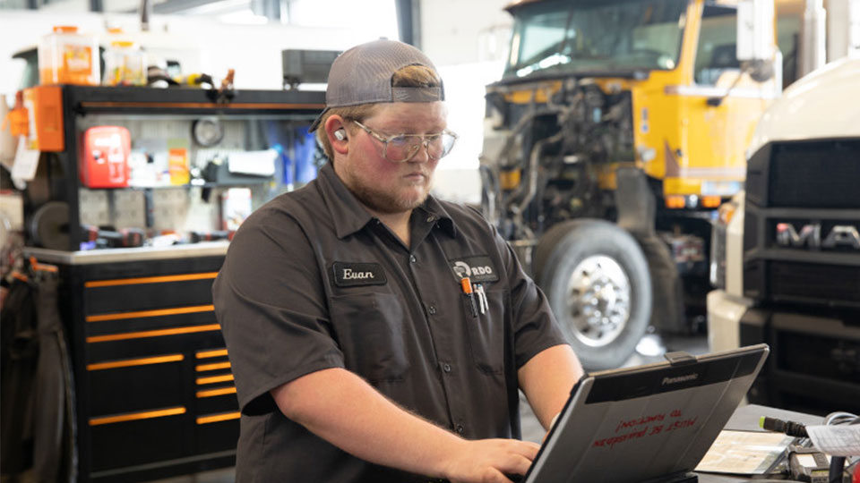 Diesel technician at computer working on work order in shop