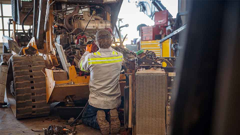 Apprentice service technician fixing engine on bulldozer