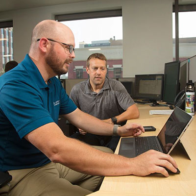 manager coaching employee at desktop computer