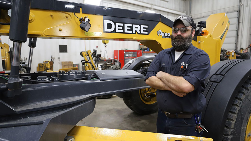 Technician standing next to John Deere construction machine