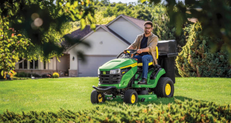 S220 John Deere riding lawn tractor mowing a yard.