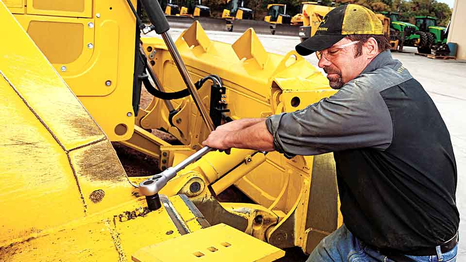 service technician using socket wrench on machine