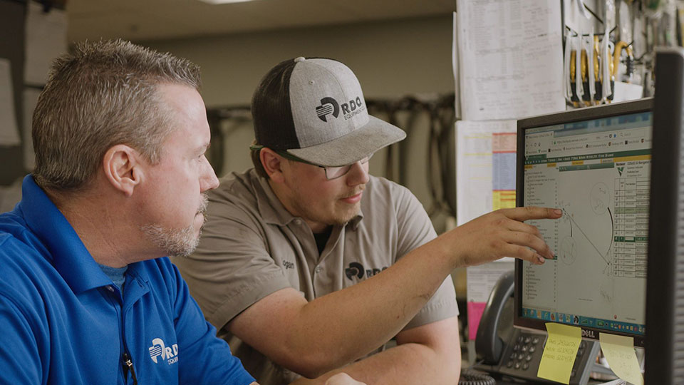 Diesel mechanic talking to supervisor pointing at computer