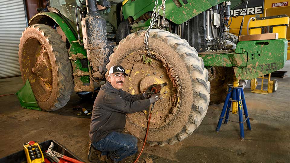 service technician fixing tire on tractor