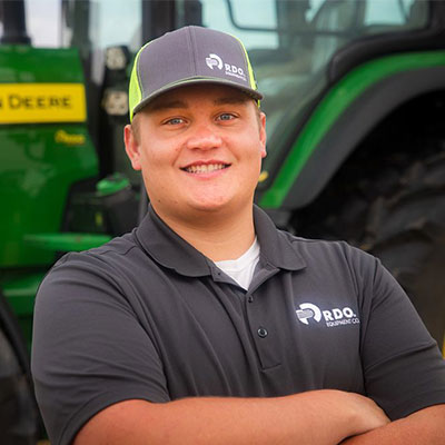 smiling sales professional green tractor in background