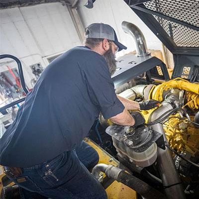 technician bent over engine diagnosing repair