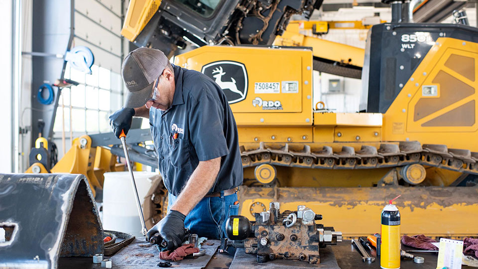 service technician in shop working on machine part