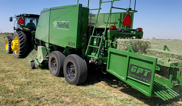 TwinPak baler being towed by a John Deere 6-series tractor.