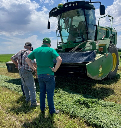 Growers look at a John Deere Windrower tractor in the field 