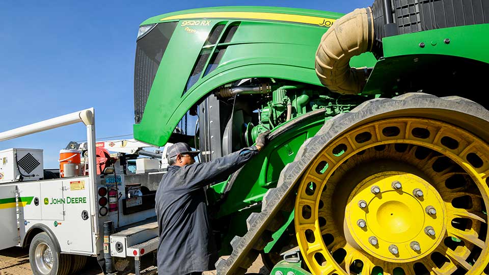 service technician fixing tractor in the field