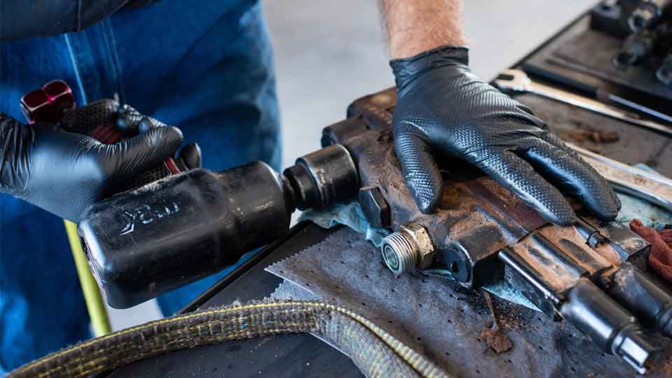 Mechanic hands using drill on machine part