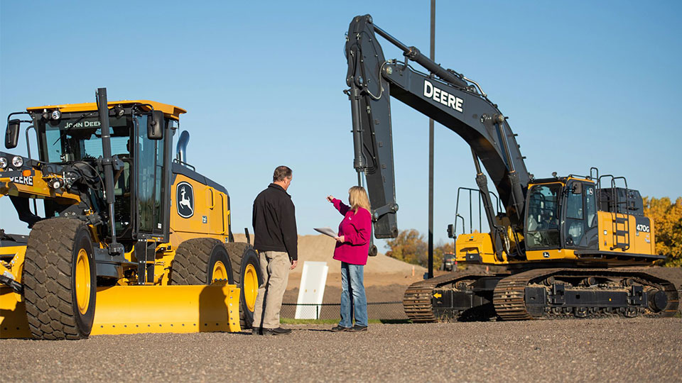 salesperson in front of construction machinery selling to customer