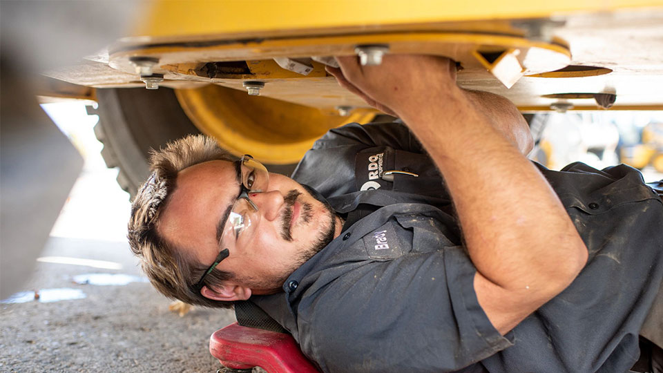 service technician under machine performing repair