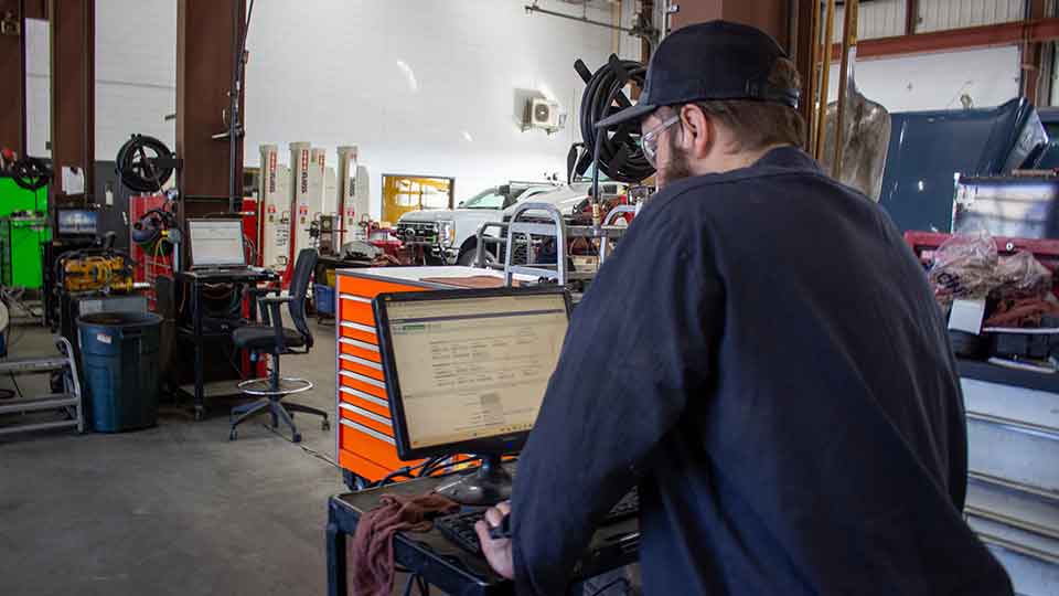 Diesel Mechanic working on computer in shop