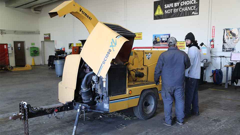 Two technicians working on Vermeer woodchipper