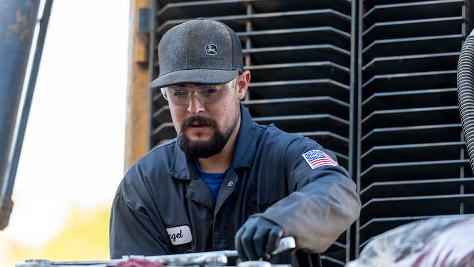 Heavy equipment mechanic turning wrench on large construction equipment