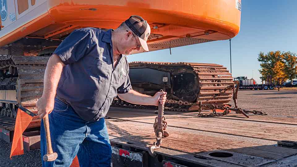 RDO Heavy Haul Truck Driver Tightening Chains on Load