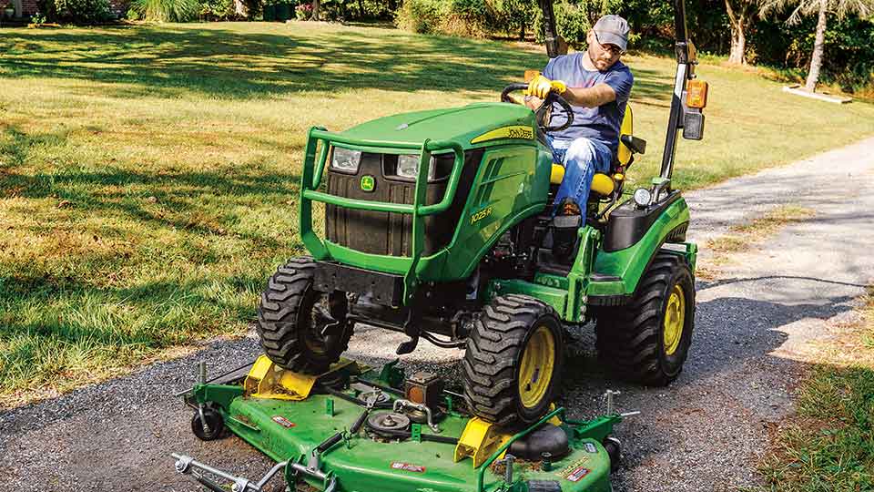 man mowing with 1025R compact utility tractor