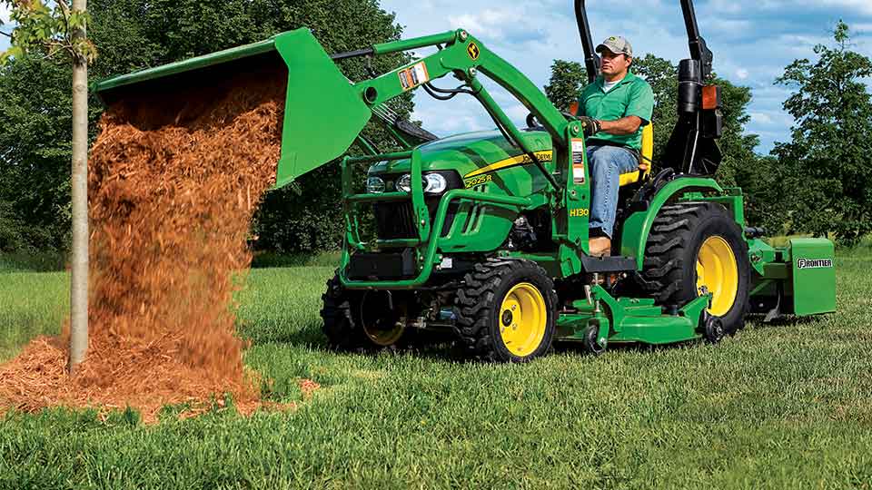 man using 2025R compact utility tractor to dump mulch