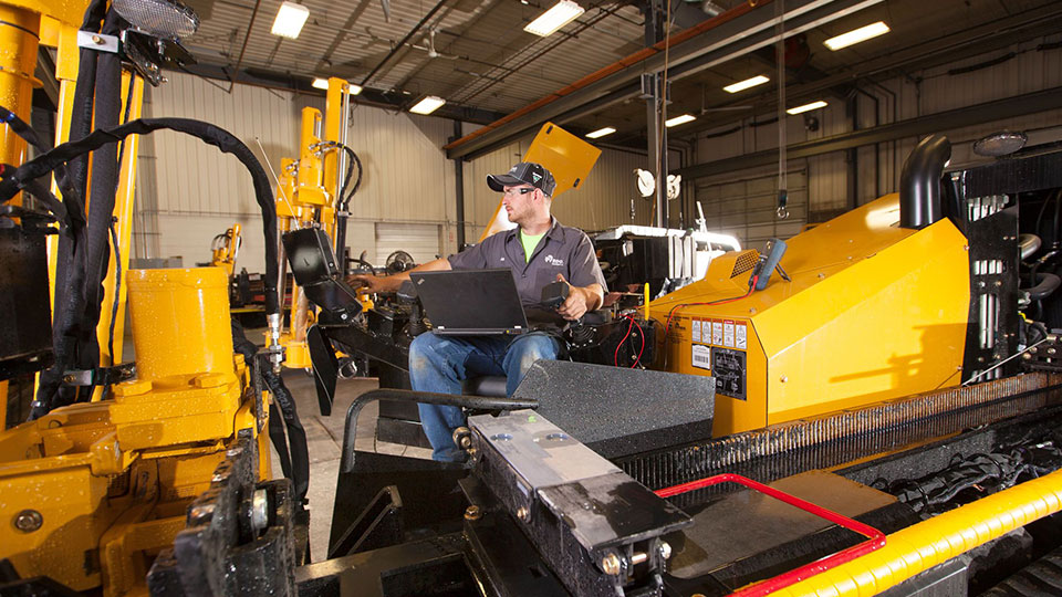 technician working on john deere machine in service shop