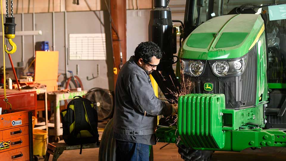 diesel mechanic welding a John Deere tractor