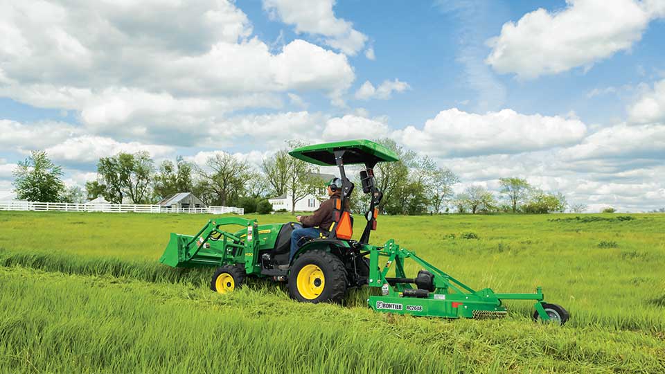 John deere compact utility tractor mowing grass on farmstead