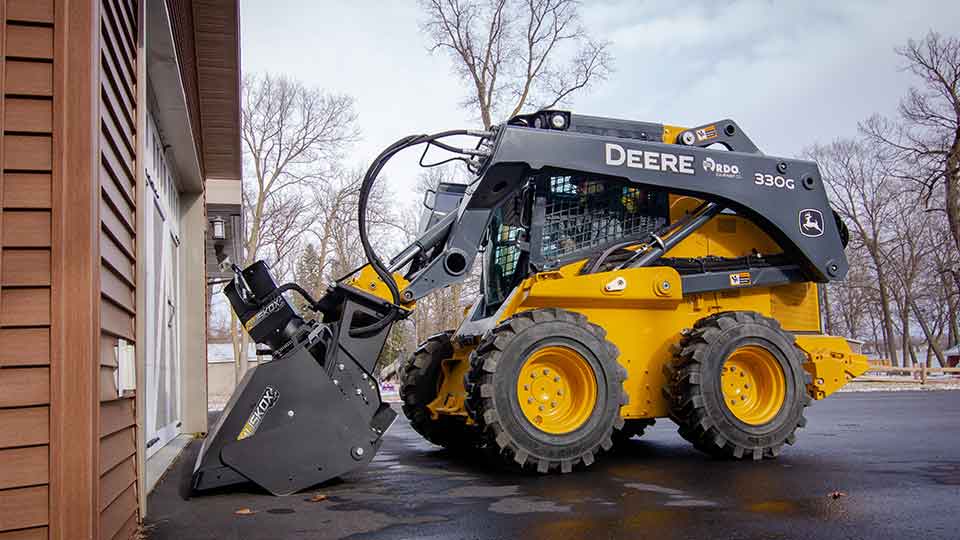 John Deere 330G skid steer working in parking lot