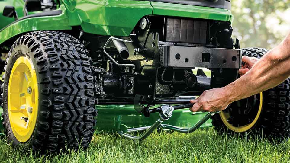 man inspecting mowing deck on riding lawn tractor
