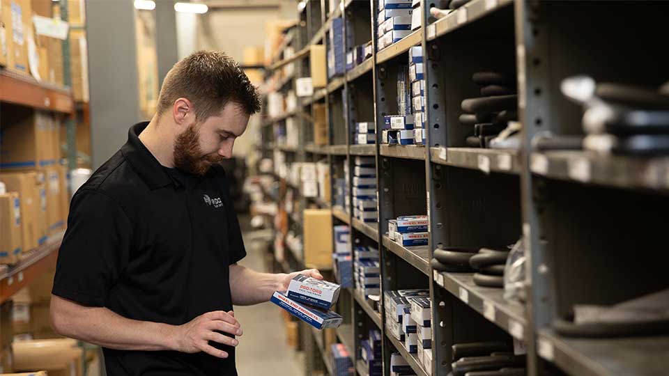 parts person looking at parts next to warehouse shelf