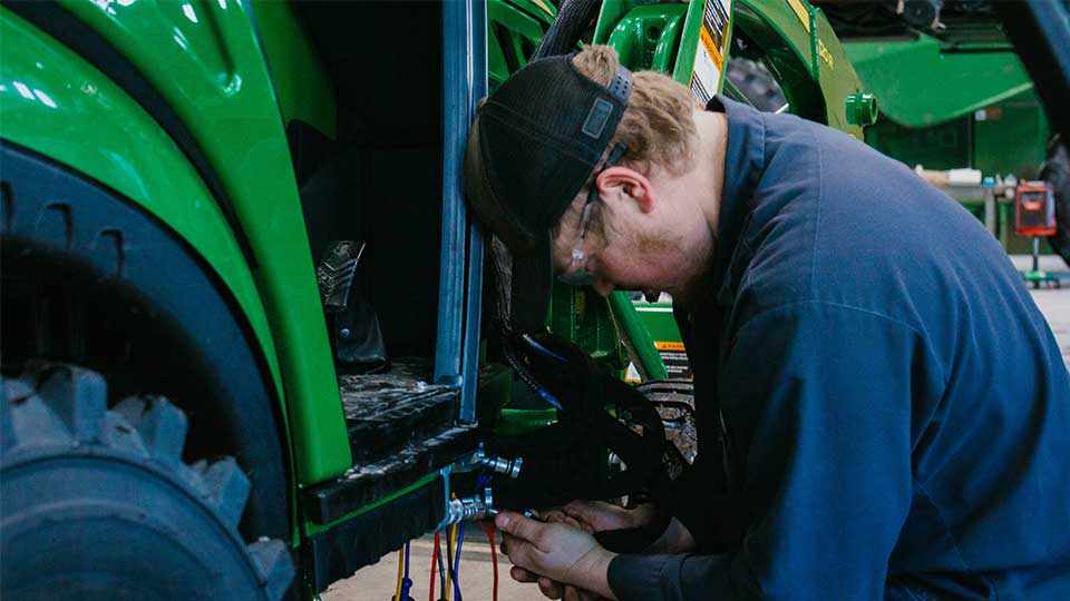 Service technician working on piece of agriculture machinery