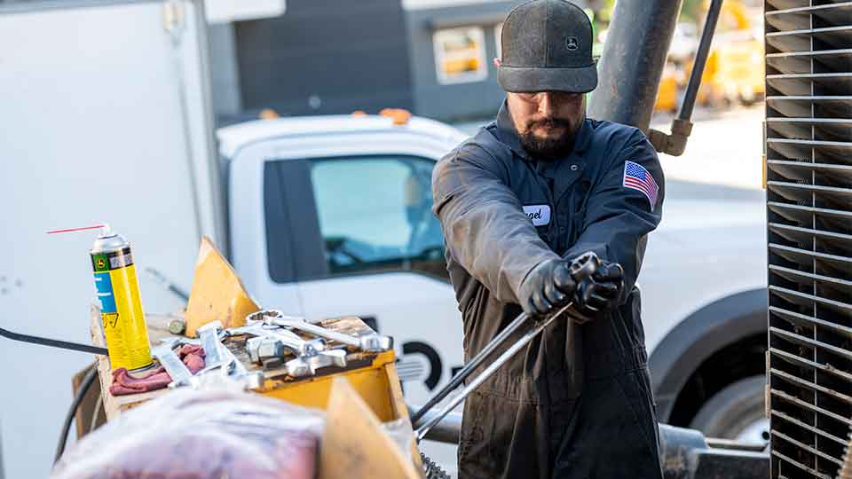 service technician using wrenches on machinery