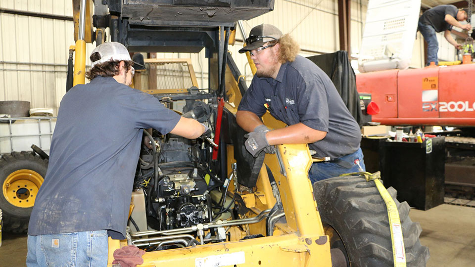 two service technicians working on compact construction equipment