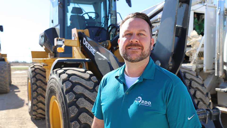 Heavy Equipment Salesperson Smiling By Backhoe