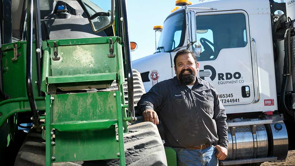 diesel mechanic standing next to John Deere tractor