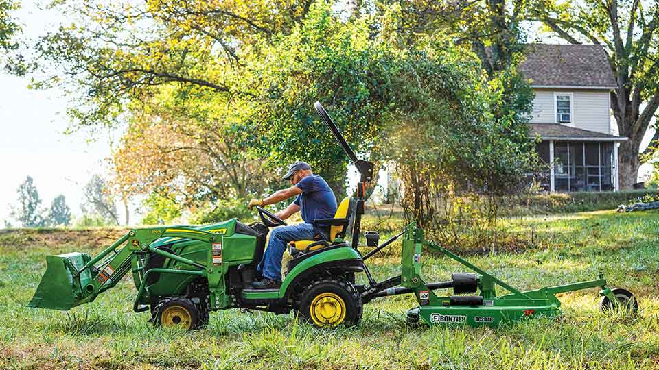 sub compact tractor cutting grass on house property