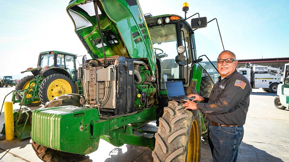 technician standing next to john deere agriculture tractor