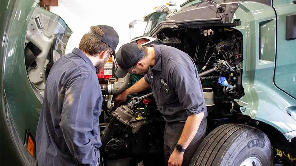 Two mechanics looking under the hood semi truck