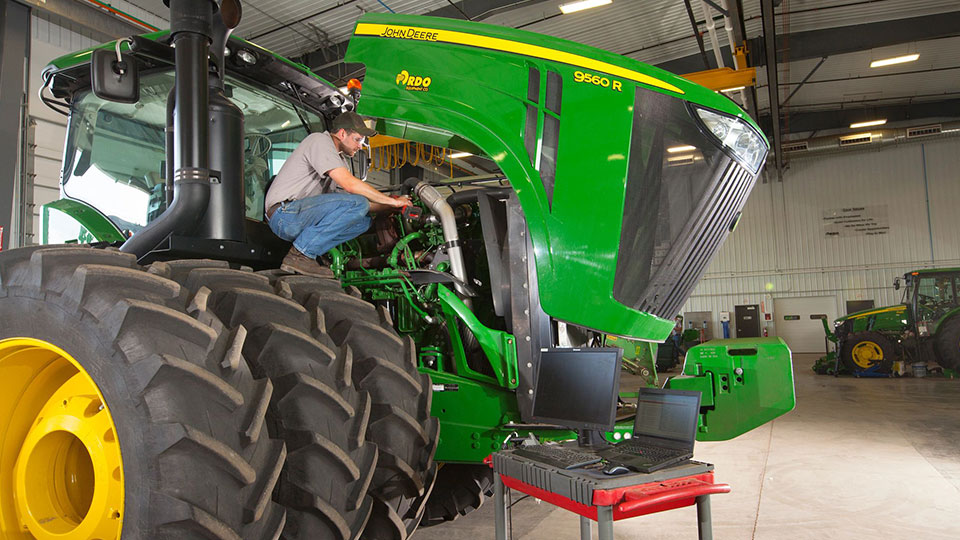 service technician on tractor working on engine