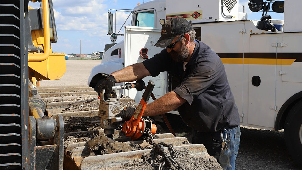 mobile technician performing repair on backhoe at construction site