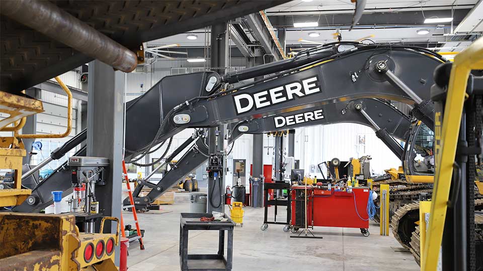 service technicians working on John Deere construction equipment in shop